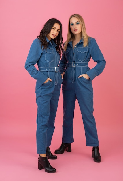 Jolies filles posant sur fond rose dans la tendance de la mode globale denim