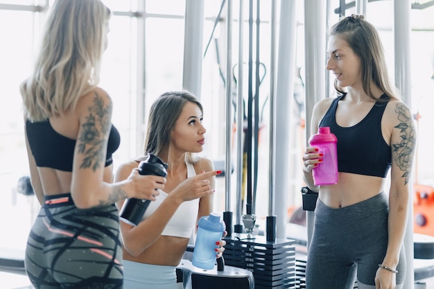 De jolies filles en tenue de sport au gymnase communiquent. vie sportive et ambiance fitness.