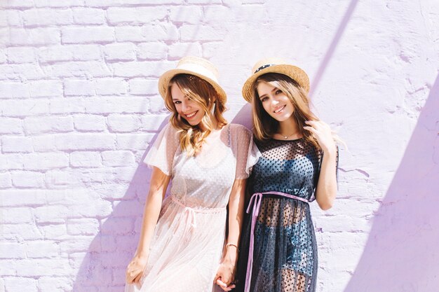 Jolies filles en vêtements d'été élégants posant ensemble après une promenade en ville et souriant