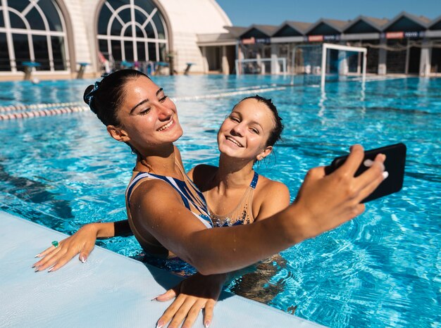 Jolies jeunes filles prenant un selfie à la piscine