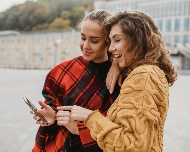 Jolies jeunes filles vérifiant un téléphone ensemble