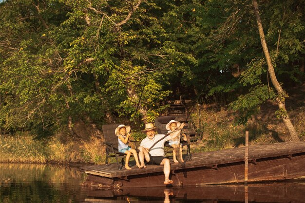 De jolies petites filles et leur grand-père pêchent au lac ou à la rivière