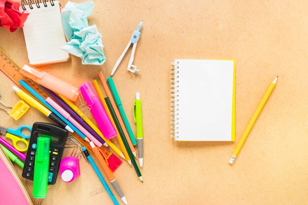 Jotter avec crayon et instruments d&#39;écriture posés de manière aléatoire