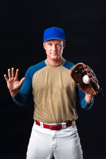 Joueur de baseball avec casquette posant avec un gant