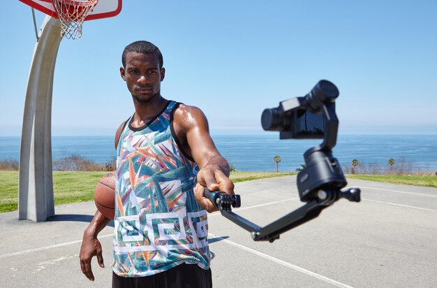 Joueur de basket au bord de l'océan avec caméra selfie