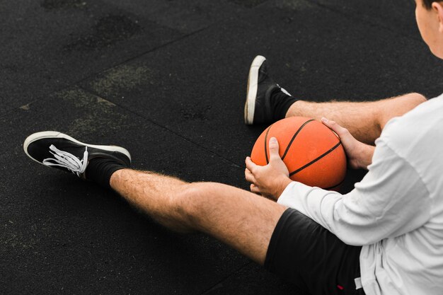 Joueur de basket méconnaissable assis sur le terrain