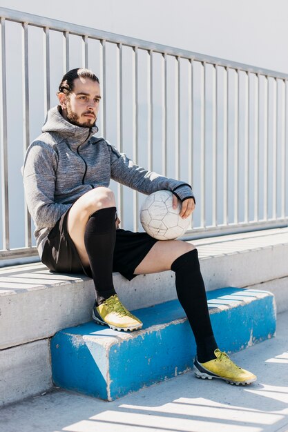 Joueur de football assis avec ballon