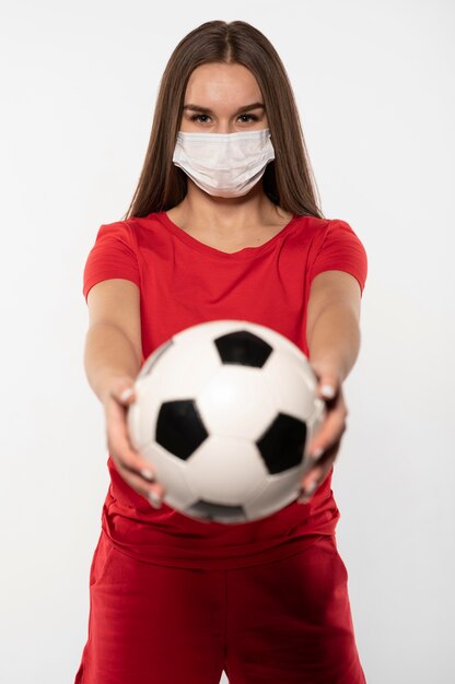 Joueur de football féminin avec masque tenant le ballon