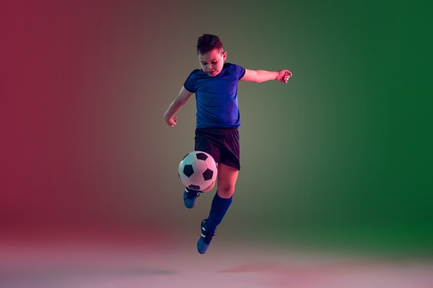 Joueur de football masculin adolescent sur mur dégradé à la lumière du néon