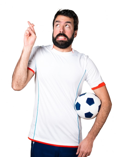 Joueur de football tenant un ballon de football avec les doigts croisés