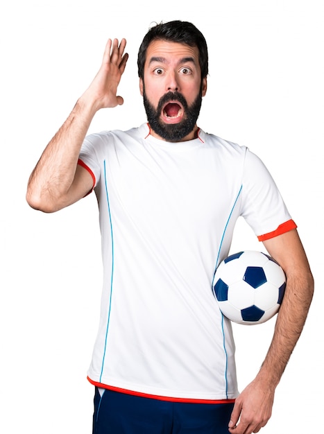 Joueur de football tenant un ballon de football faisant un geste de surprise