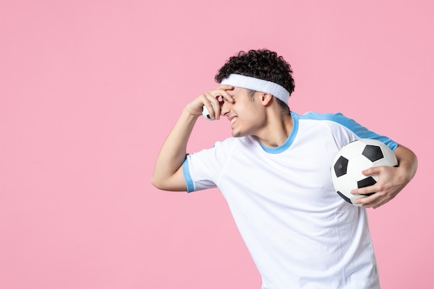 Joueur de football vue de face en vêtements de sport avec ballon