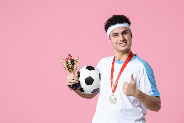 Joueur de football vue de face en vêtements de sport avec coupe d'or et médaille