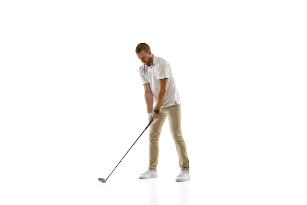 Joueur de golf dans une chemise blanche prenant un swing isolé sur un mur blanc avec copyspace. Joueur professionnel pratiquant avec des émotions vives et une expression faciale. Concept de sport.