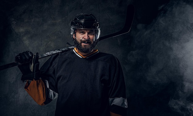 Photo gratuite un joueur de hockey édenté heureux pose pour un photographe avec un bâton de hockey.