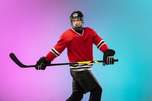 Joueur de hockey masculin avec le bâton sur la patinoire et fond dégradé de couleur néon