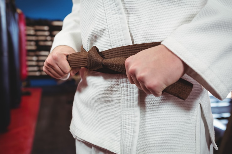 Photo gratuit joueur de karaté attachant sa ceinture