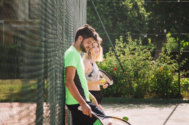 Photo gratuite les joueurs de tennis s'appuient sur une clôture