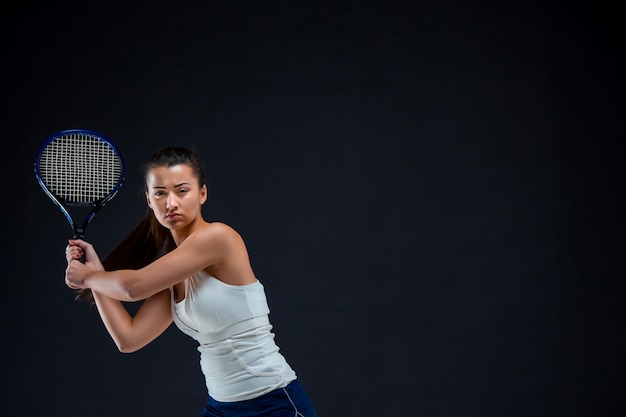 Joueuse de tennis belle fille avec une raquette sur fond sombre