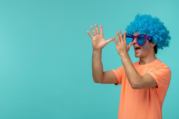 Photo gratuite jour du poisson d'avril gars clown plaisantant cheveux bleus roses grosses lunettes de soleil drôle touchant le bout de son nez