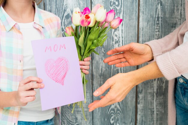 Jour de la mère de la carte postale et des tulipes dans les mains de la fille