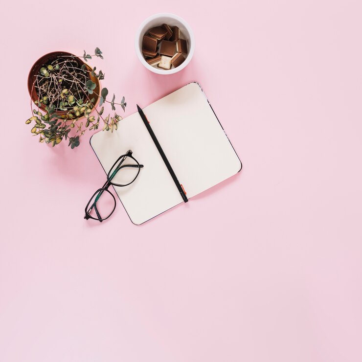 Photo gratuit journal intime avec stylo; lunettes; showplant et morceaux de chocolat dans un gobelet en plastique
