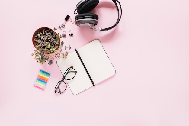Un journal ouvert blanc et un stylo avec papeterie sur fond rose