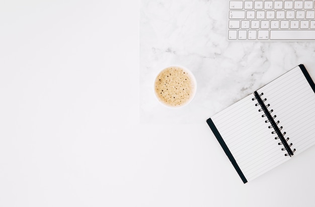 Un journal ouvert; café et clavier sur le bureau sur fond blanc