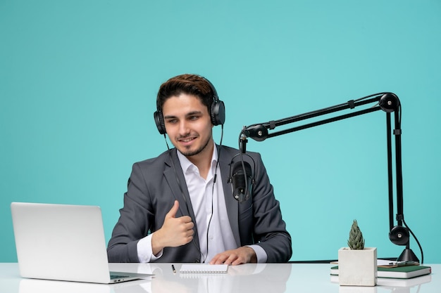 Journaliste blogueur jeune beau mec mignon en costume gris enregistrant une vidéo montrant un signe ok