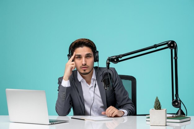 Journaliste blogueur jeune beau mec mignon en costume gris enregistrant une vidéo pensant et concentré