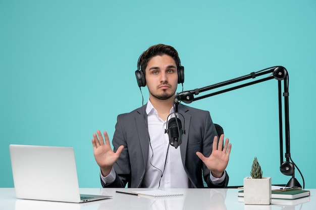 Journaliste blogueur sérieux beau mec mignon enregistrant une vidéo en costume gris s'arrêtant les mains