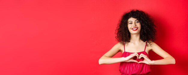 Journée des amoureux belle femme célébrant la Saint-Valentin montrant le signe du coeur et souriant debout en romanti