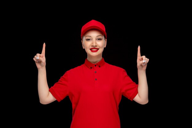 Journée de la chemise rouge excitée jolie dame pointant les doigts vers le haut dans un bonnet rouge portant une chemise avec du rouge à lèvres