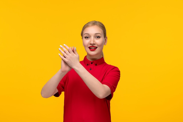 Photo gratuit journée de la chemise rouge fille heureuse frappant des mains dans une chemise rouge sur fond jaune