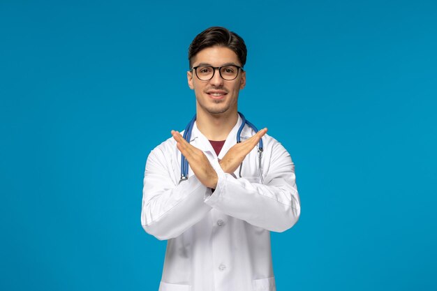 Journée des médecins beau mec mignon brune en blouse médicale croisant les mains