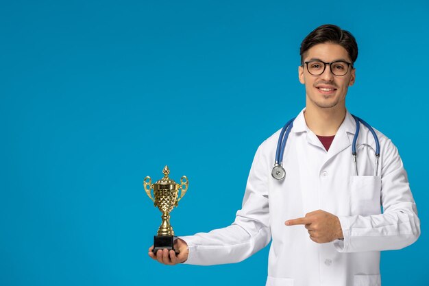 Journée des médecins beau mec mignon brune en blouse médicale tenant un trophée
