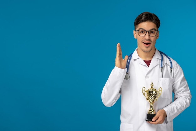 Journée des médecins beau mec mignon brune en blouse médicale tenant le trophée