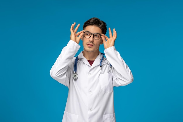 Journée des médecins beau mec mignon brune en robe médicale tenant des lunettes