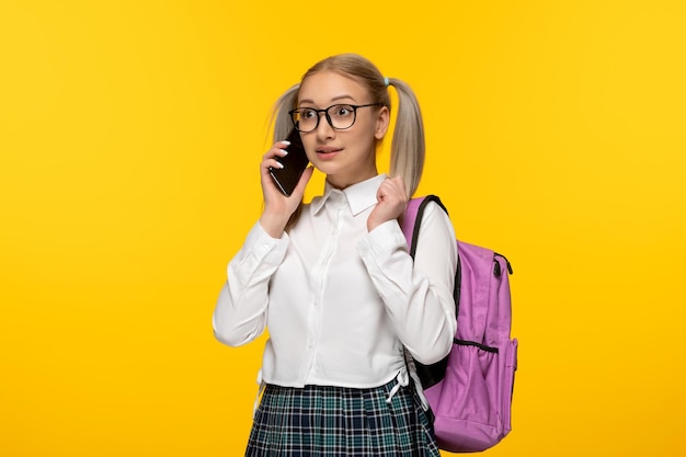 Journée mondiale du livre écolière blonde parlant au téléphone portable sur fond jaune