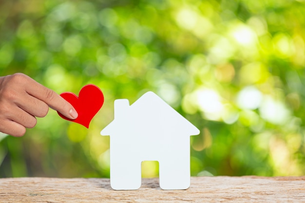 Journée mondiale de l'habitat, gros plan photo d'une maison modèle et main tenant un coeur en papier
