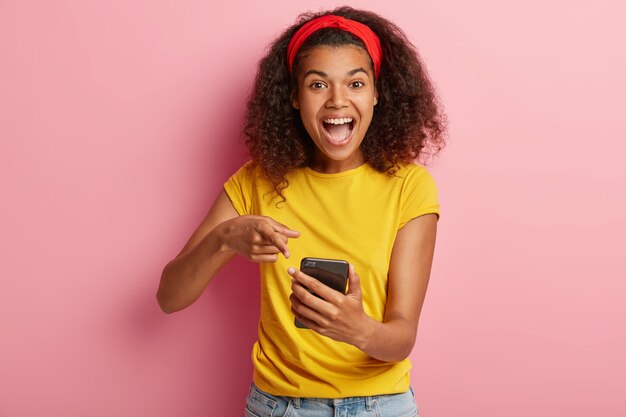 Joyeuse belle adolescente aux cheveux bouclés posant en tshirt jaune