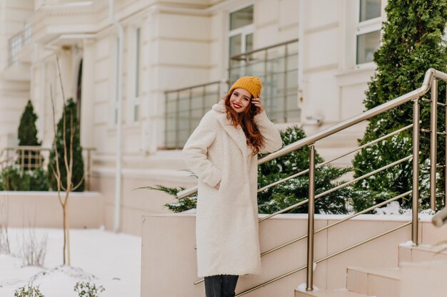 Joyeuse belle femme posant le matin d'hiver Photo en plein air d'un joli modèle féminin marchant dans la rue