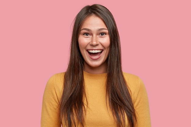 Joyeuse belle fille brune, sourit de bonheur, se sent joyeuse et amusée