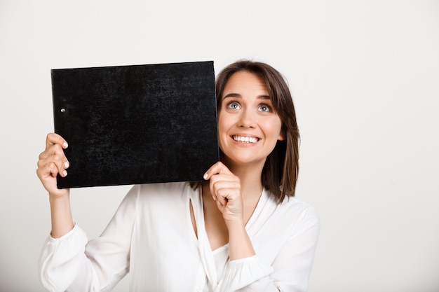 Joyeuse dame de bureau montrant la bannière sur le presse-papiers noir