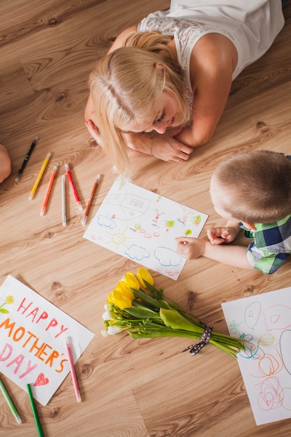 Joyeuse femme allongée sur le sol avec son fils