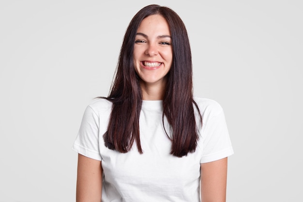 Joyeuse femme brune satisfaite a un sourire à pleines dents, être de bonne humeur exprime des émotions positives