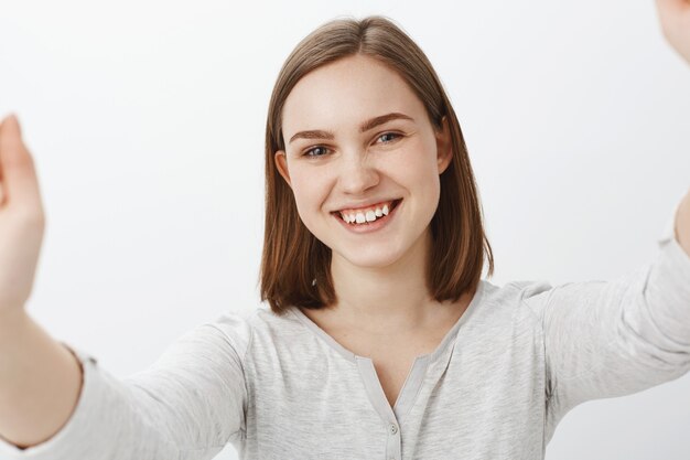 joyeuse femme brune en tenue décontractée prenant selfie et souriant largement