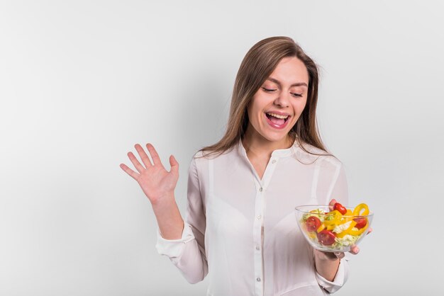 Joyeuse femme debout avec une salade de légumes dans un bol