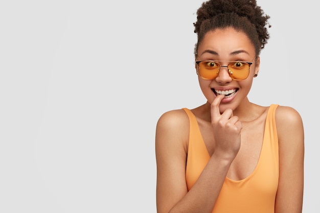 Joyeuse femme à la peau sombre excitée garde le doigt avant près des dents