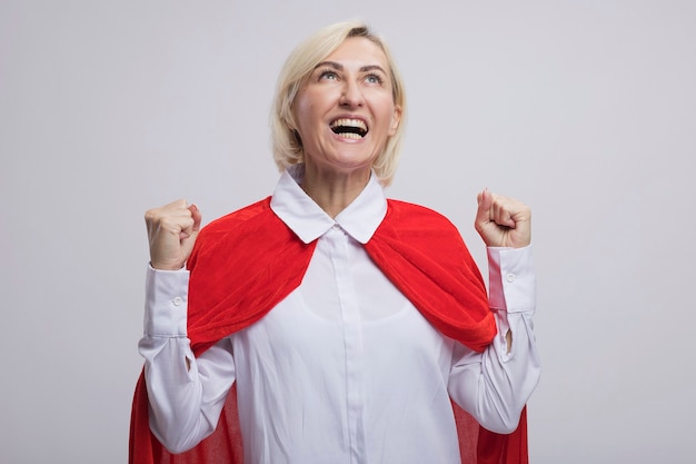 Joyeuse femme de super-héros blonde d'âge moyen en cape rouge faisant un geste oui en levant